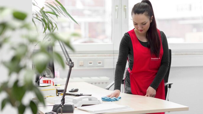 Dussmann Facility Management Woman cleans desk