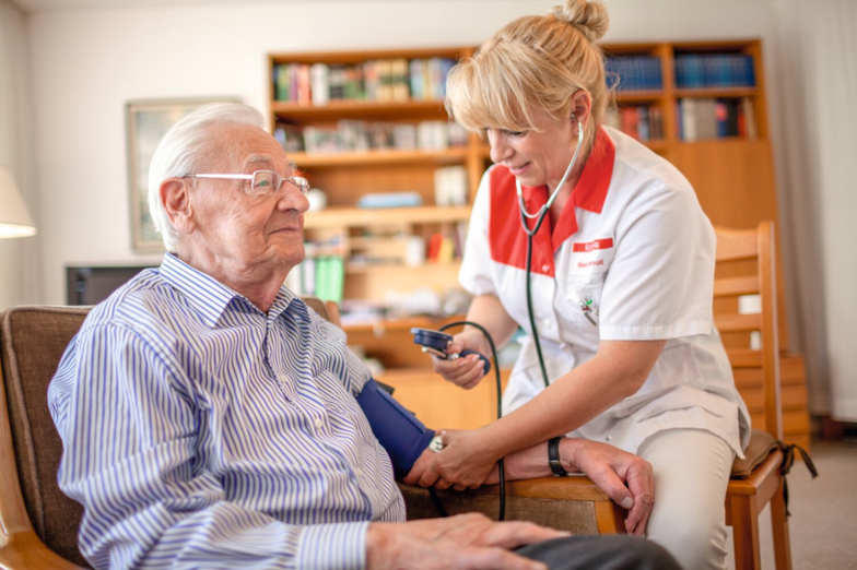 Care service provider Kursana Nurse measures patient's blood pressure