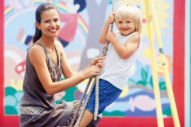 Dussmann KulturKindergarten Educator swinging with child