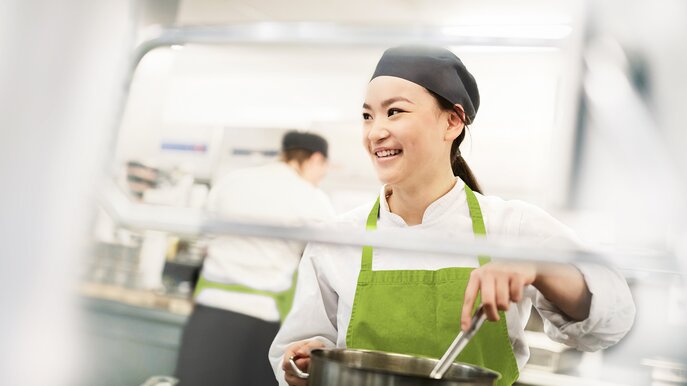 Dussmann Food Services Cook stirs in cooking pot