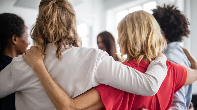 Social part of the Dussmann Group's ESG strategy People stand in circle and hug each other